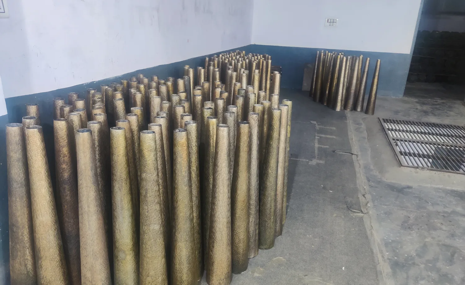 Large production batch of hammered metal vases arranged for readiness review